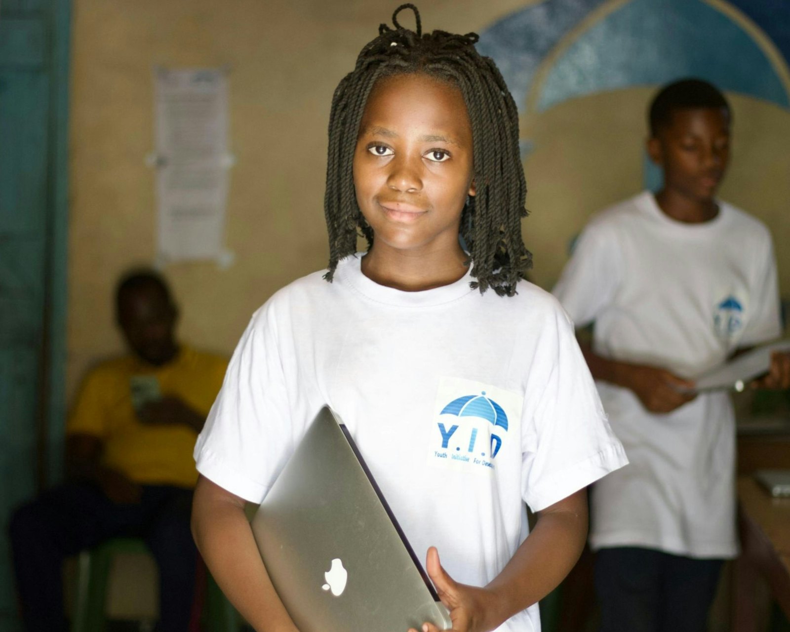 Young girl holding a laptop in her classroom